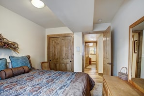A bedroom with a bed, wooden wardrobe, and a hallway leading to another room.
