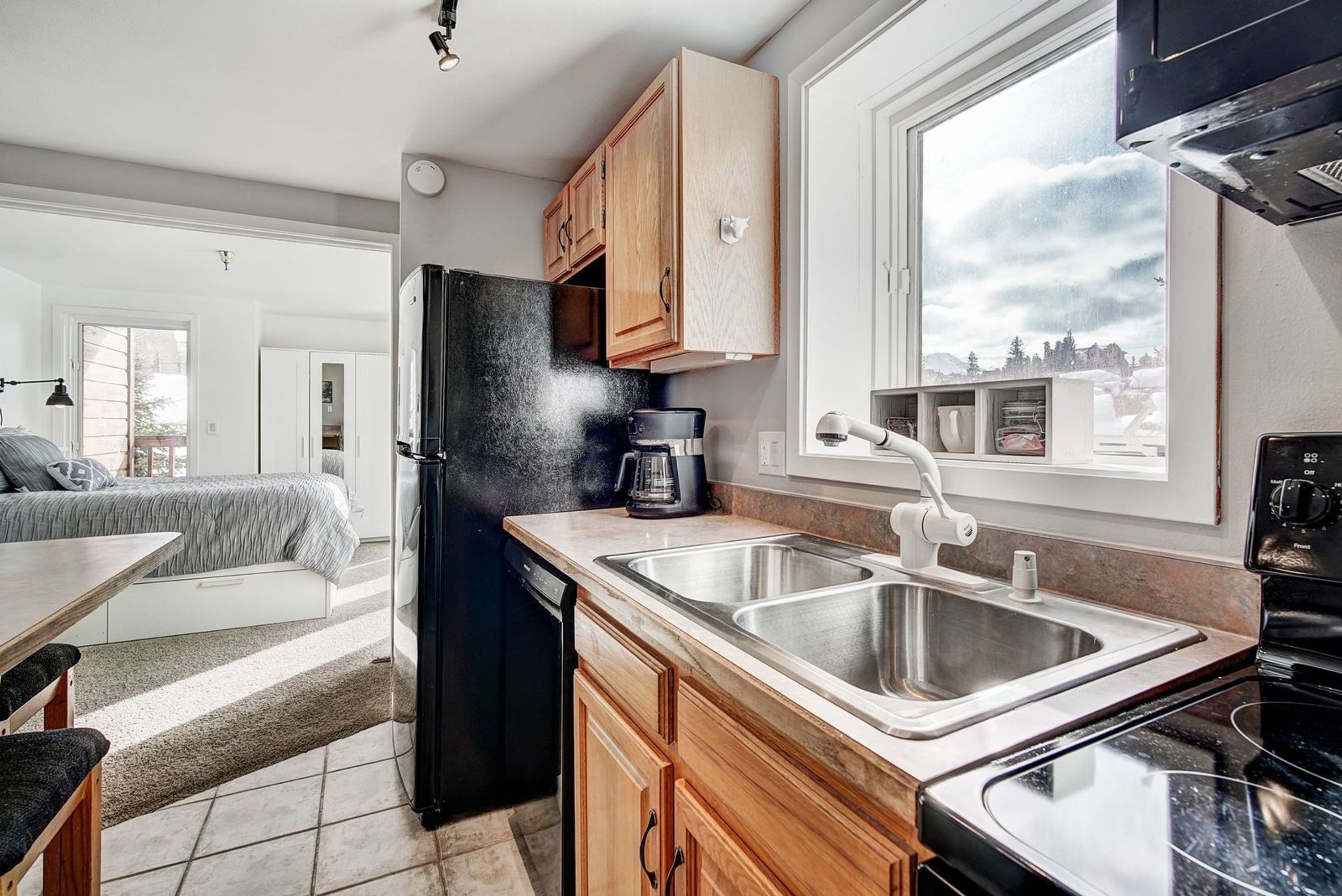 A compact kitchen with a refrigerator, coffee maker, and double sink.