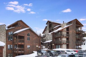 A multi-story wooden building with balconies, a stone facade, and a parking lot with cars. - Tyra Lookout #22 in Breckenridge (Breckenridge)