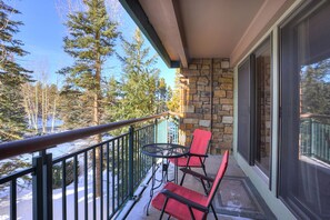 A balcony with a stone wall, a metal railing, and two red chairs. - Trails End 201 in Breckenridge (Breckenridge)