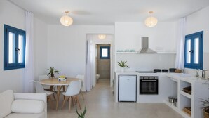 A compact living space with a kitchenette, dining area, and a sofa. - White Wave Houses (Santorini)