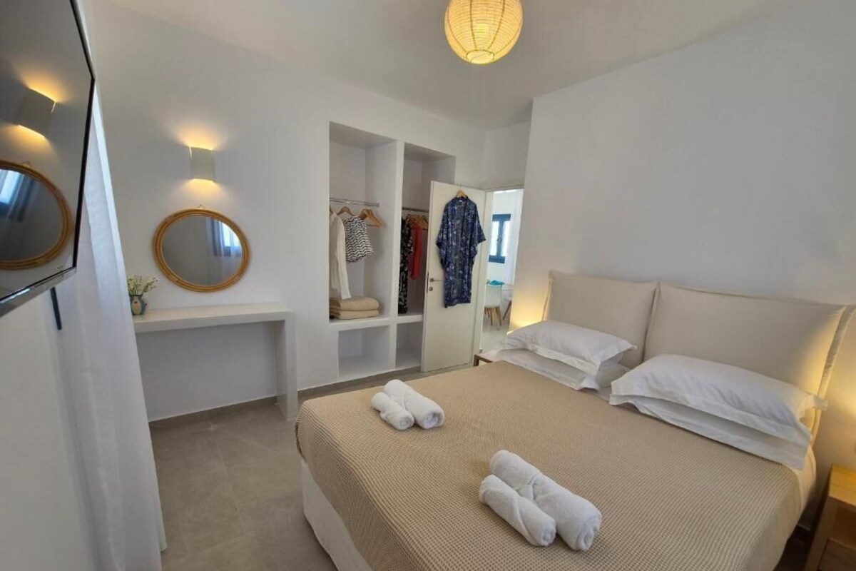 A hotel room with a bed, bedside tables, a mirror, and a wardrobe.