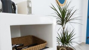 A white shelving unit with wicker baskets and a potted plant. - White Wave Houses (Santorini)