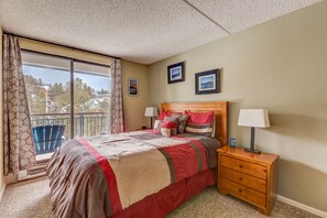 A bedroom with a large bed, a nightstand, a window with curtains, and a balcony. - Trails End 509 in Breckenridge (Breckenridge)