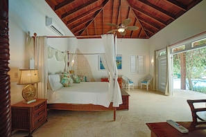 A bedroom with a wooden ceiling, a bed with a canopy, a nightstand, a chair, and a view of the outdoors. - Villa Casamare Oceanfront Luxury in SeaHorseRanch (Sosúa)