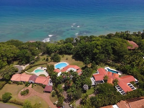 An aerial view of a resort with multiple swimming pools, lush greenery, and a beach. - Villa Casamare Oceanfront Luxury in SeaHorseRanch (Sosúa)