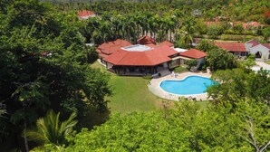 A residential property with a swimming pool, surrounded by lush greenery and multiple buildings with red-tiled roofs. - Villa Casamare Oceanfront Luxury in SeaHorseRanch (Sosúa)