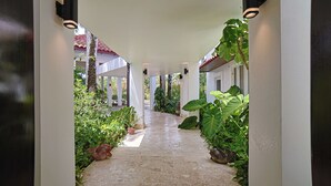 A corridor with white walls, columns, and potted plants. - Villa Casamare Oceanfront Luxury in SeaHorseRanch (Sosúa)