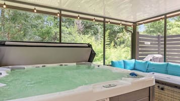 Ett bubbelbad med utsikt över grönskan, en överbyggd sittplats och en varningsetikett.