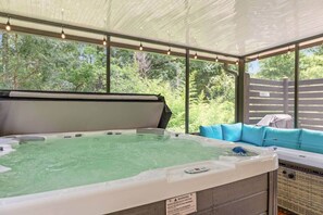 Un bain à remous avec vue sur la verdure, un espace salon couvert et une étiquette d’avertissement.