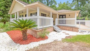 A two-story house with a covered porch, a small front yard with red mulch, and a palm tree. - Sizzlin Farmhouse in Carencro (Lafayette Parish)