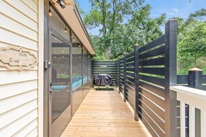 A wooden deck with a glass door leading to a porch, a barbecue grill, and a sign welcoming guests. - Sizzlin Farmhouse in Carencro (Lafayette Parish)