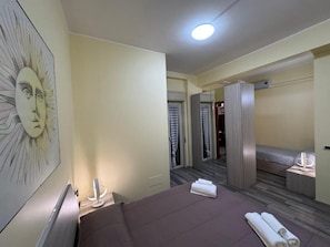 Une chambre d’hôtel comprenant un lit, une table de chevet, un miroir, une armoire et une salle de bain avec douche et toilettes.
