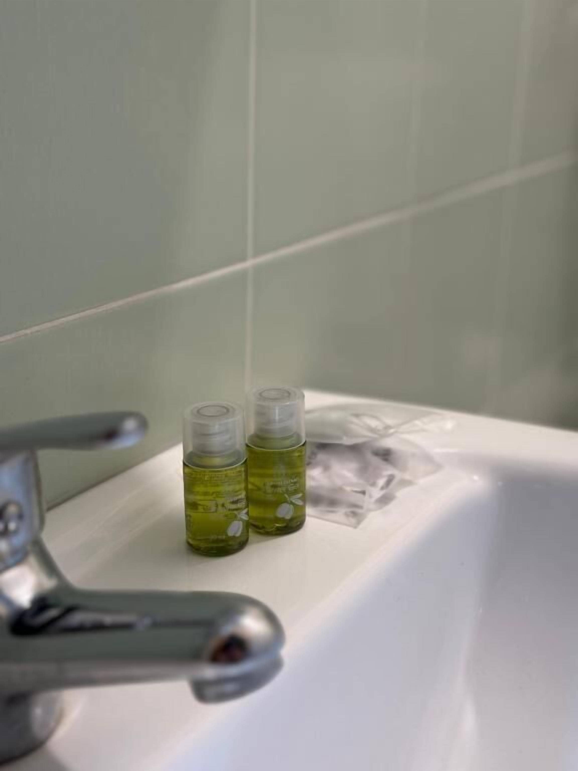 A bathroom sink with two bottles of liquid and a plastic bag on the counter.