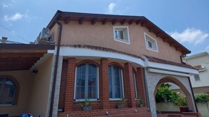 A two-story house with a red brick facade, multiple windows, and a flat roof. - Apartment 'Dea' with Shared Pool, Wi-Fi, and Air Conditioning (Arenella)