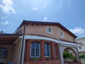 Ein zweistöckiges Haus mit roter Backsteinfassade, zahlreichen Fenstern und einem Flachdach.