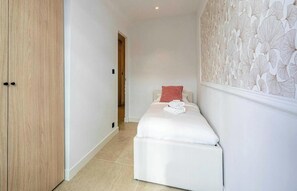 A small, neatly arranged bedroom with a bed, a wardrobe, and a wall with a leaf pattern. - IDEALLY LOCATED JUST A SHORT STROLL FROM THE ICONIC BOULEVARD DE LA CROISETTE (Cannes)