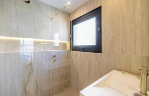 Ein modernes Badezimmer mit Dusche, Waschbecken und Fenster.