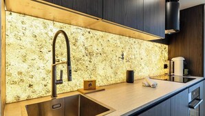A modern kitchen with a granite backsplash, stainless steel sink, and a coffee machine.