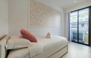 A modern hotel room with a large bed, a decorative wall piece, and a view of the building's exterior through a glass door. - IDEALLY LOCATED JUST A SHORT STROLL FROM THE ICONIC BOULEVARD DE LA CROISETTE (Cannes)