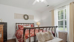 Una camera da letto con un letto, un comodino, una lampada e una finestra con tende.