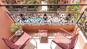Ein Balkon mit Pool, zwei Stühlen, einem Tisch und einer Topfpflanze.