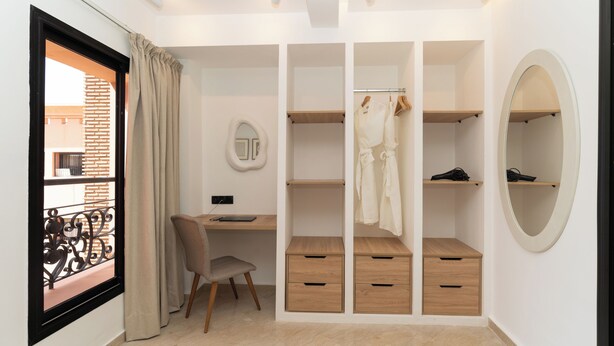 Ein Schlafzimmer mit einem Bett, einem Schreibtisch, einem Stuhl, einem Kleiderschrank und einem Fenster mit Vorhängen.
