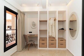 Un dormitorio con cama, escritorio, silla, armario y ventana con cortinas.