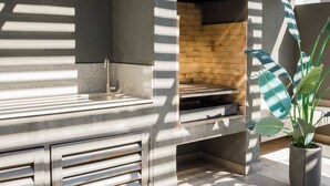 Una cocina al aire libre con horno de ladrillo, pileta integrada y cajones de almacenamiento.
