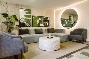A modern living room with a grey sofa, a round coffee table, and a large mirror. - 1BR1BA Downtown Santiago Cozy Urban Retreat for 3 (Santiago)