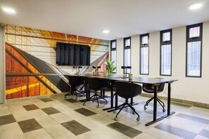 A conference room with a large table, four chairs, a flat-screen TV, and a mural on the wall. - 1BR1BA Downtown Santiago Cozy Urban Retreat for 3 (Santiago)