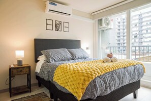 A bedroom with a bed, bedside table, lamp, and artwork on the wall. - 1BR1BA Downtown Santiago Cozy Urban Retreat for 3 (Santiago)