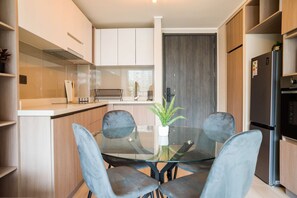 A modern kitchen with a glass dining table, two chairs, and a refrigerator. - 1BR1BA Downtown Santiago Cozy Urban Retreat for 3 (Santiago)