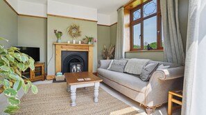 A living room with a fireplace, sofa, coffee table, and a television. - Tranquil countryside cottage (Wrexham)