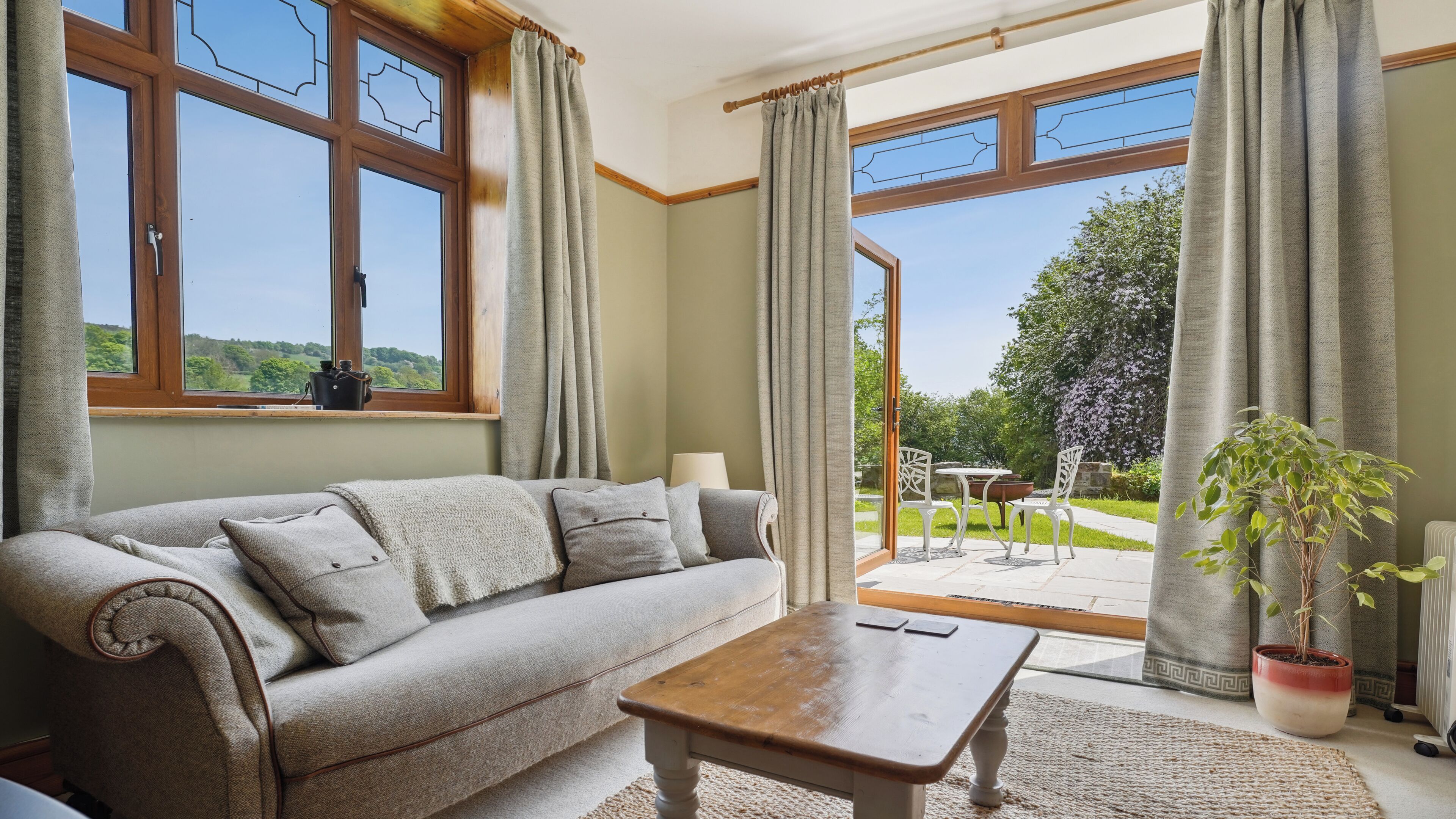 A living room with a sofa, a coffee table, and a view of the outdoors through large windows.