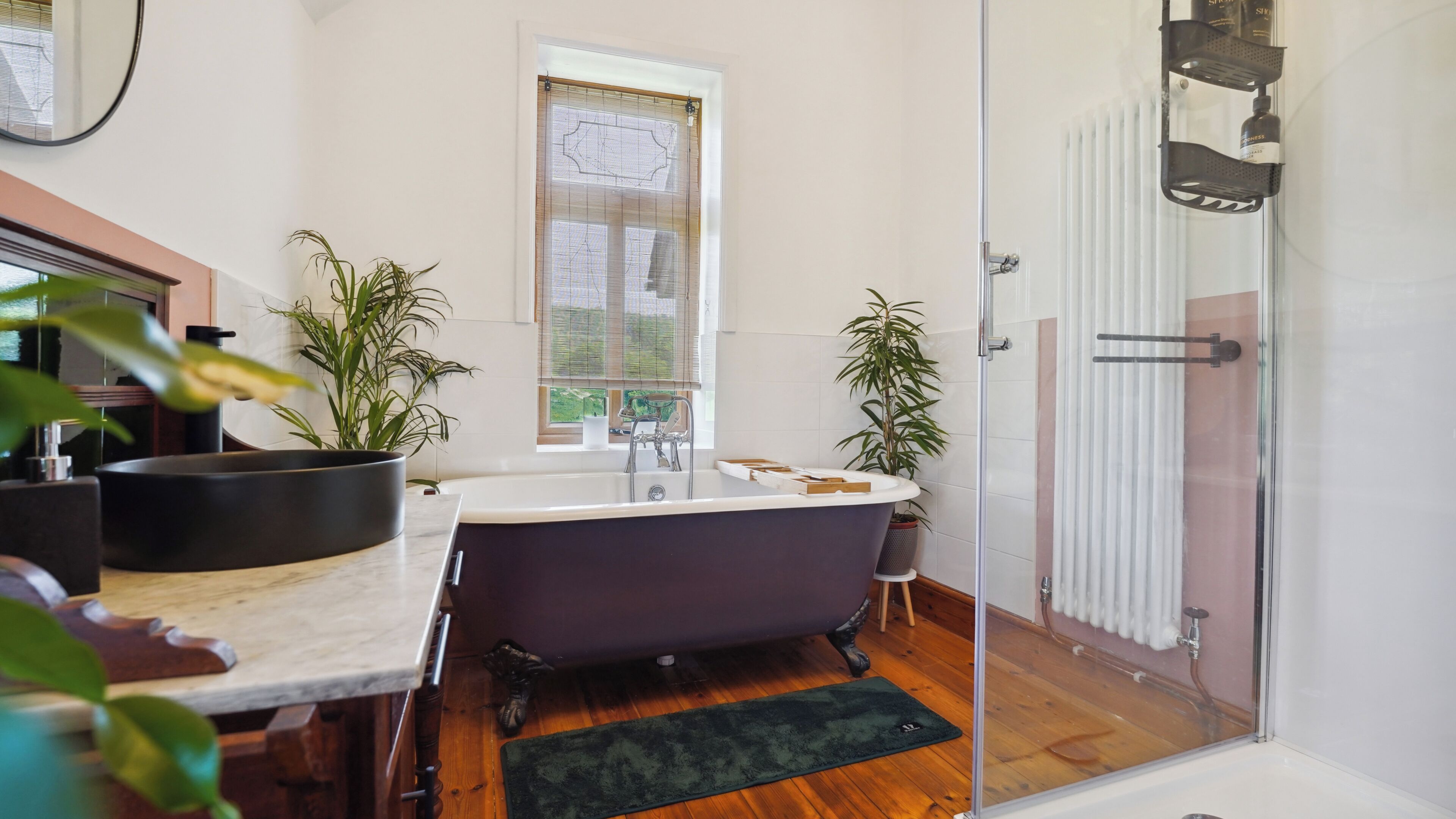 Une salle de bain moderne avec une baignoire sur pieds, un espace douche et une fenêtre laissant entrer la lumière naturelle.
