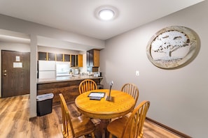 A modern kitchen with wooden cabinets, a central island, and a dining area with a round table and chairs.