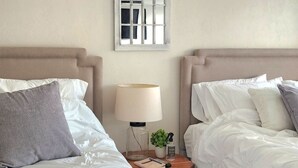 Une chambre d’hôtel avec deux lits, une table de chevet, une lampe et un miroir décoratif.