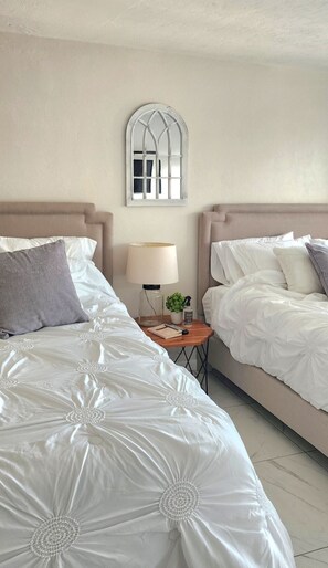 A hotel room with two beds, a nightstand, a lamp, and a decorative mirror. - Marco Island --- Stay in Paradise! (Marco Island)
