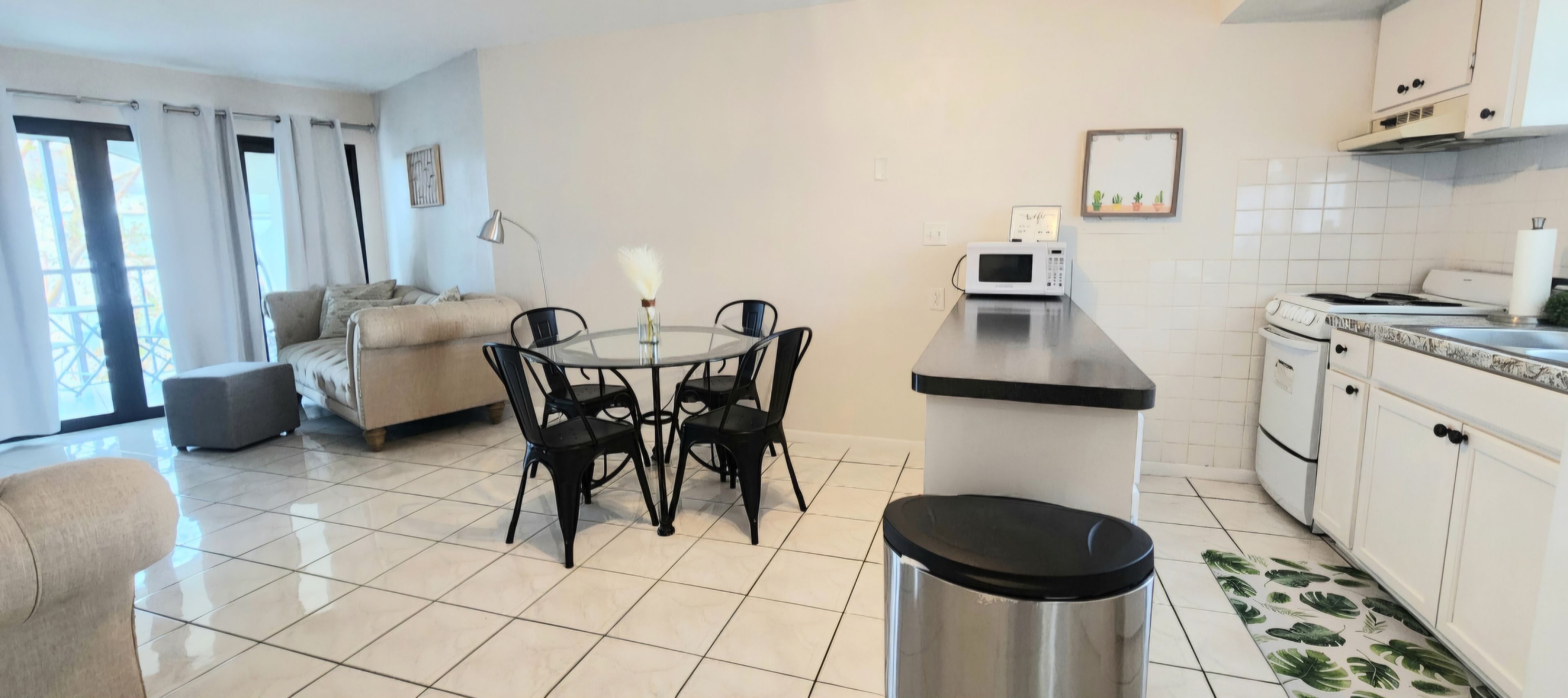 A compact living space with a kitchenette, a dining area with a round table and chairs, and a sofa.