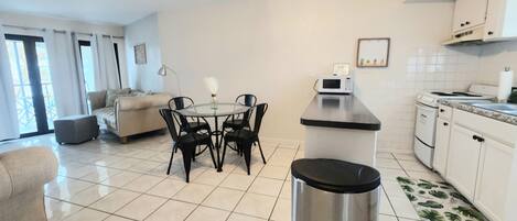 A compact living space with a kitchenette, a dining area with a round table and chairs, and a sofa.