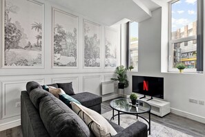 A modern living room with a sofa, a coffee table, and a TV displaying the Netflix logo. - Modern 1BR Flat in Leeds - WiFi (Leeds)