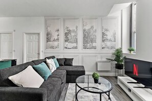 A modern living room with a sectional sofa, a glass coffee table, and a fireplace. - Modern 1BR Flat in Leeds - WiFi (Leeds)