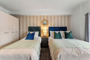 Ein Hotelzimmer mit zwei Betten, einem großen Spiegel und einem Nachttisch mit einer Lampe.