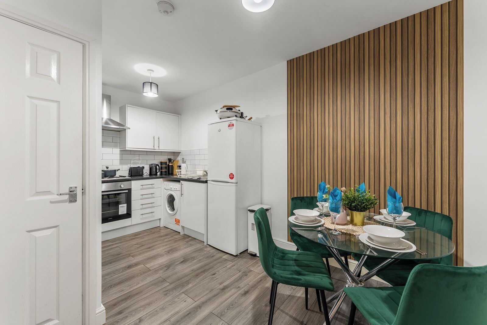 A modern kitchen with white cabinets, a built-in oven, and a refrigerator.