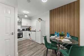 A modern kitchen with white cabinets, a built-in oven, and a refrigerator. - The Wesley Flat | Elegant Leeds Retreat (Leeds)