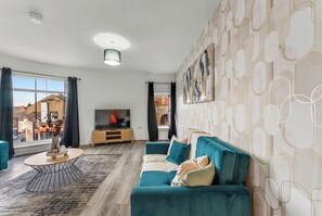 Ein modernes Wohnzimmer mit einer Couch, einem Fernseher und einem großen Fenster.
