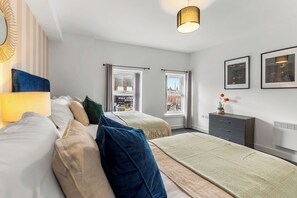 A modern hotel room with two beds, a dresser, a lamp, and framed artwork on the walls. - The Wesley Flat | Elegant Leeds Retreat (Leeds)