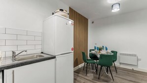 A compact kitchen with a sink, a white refrigerator, and a dining area with a table and chairs.