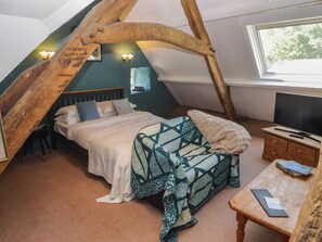 Une chambre confortable située dans les combles, avec un lit, une télévision et une fenêtre.